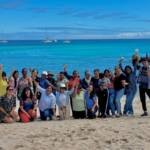 Foto grupal de guardianas azules y el equipo de Fundación Ola Igualdad en el taller de liderazgo, género y empoderamiento emocional en la playa, en San Cristóbal