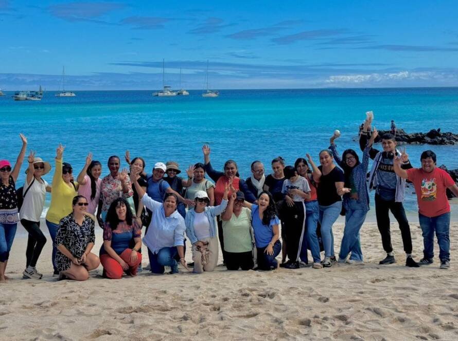 Foto grupal de guardianas azules y el equipo de Fundación Ola Igualdad en el taller de liderazgo, género y empoderamiento emocional en la playa, en San Cristóbal