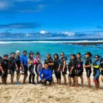 Foto grupal de Guardianas azules con instructor de natación Alex Nata, con trajes de buceo en el taller de habilidades acuáticas y monitoreo comunitario en Isla Lobos